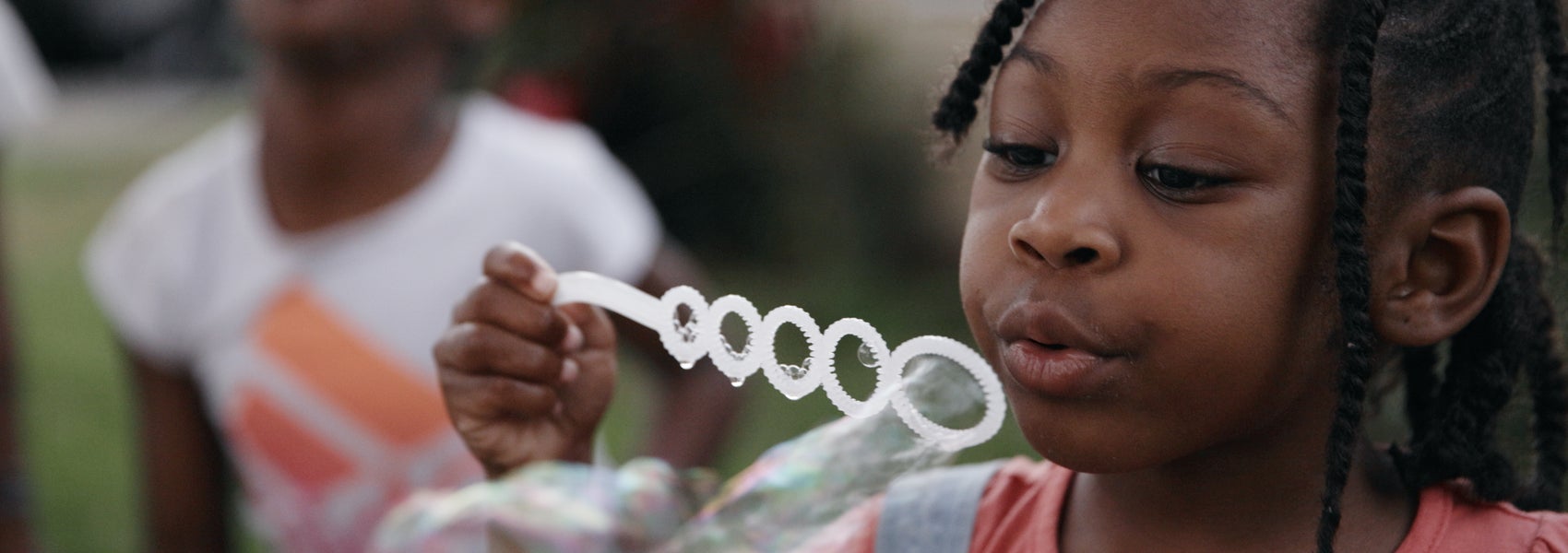 A young girl blows bubbles with her sister